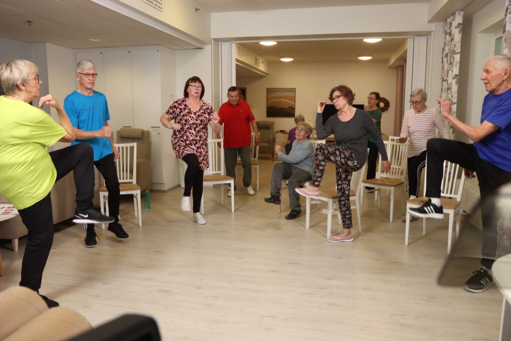 Kuvassa senioritalon asukkaat jumppaavat yhdessä vapaaehtoisen johdolla.