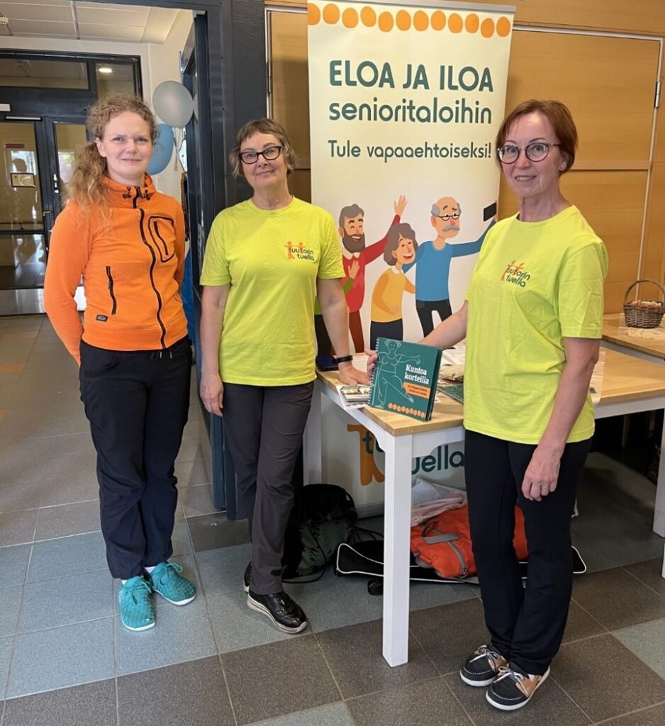 Kuvassa vapaaehtoiset esittelevät toimintaa yhdessä ammattilaisen kanssa paikallisessa tapahtumassa.