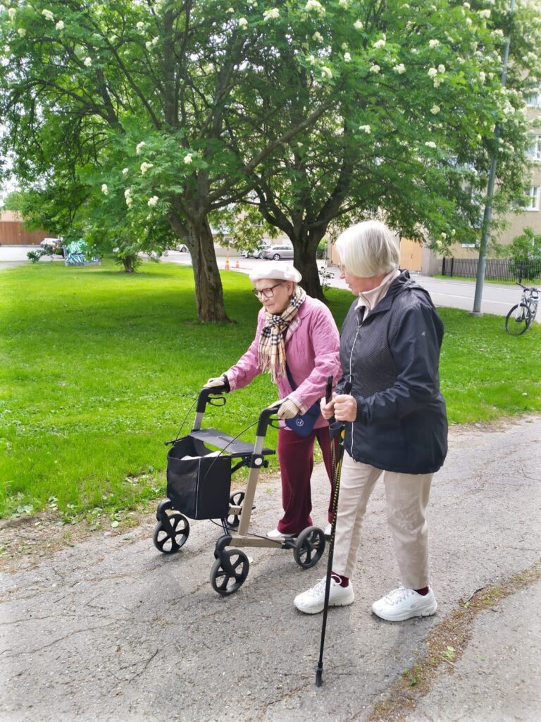 Kuvassa vapaaehtoinen ulkoilee yhdessä iäkkään kanssa.